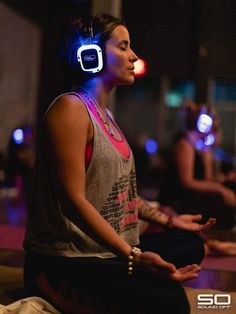 a woman sitting on the floor with headphones in her ears