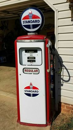 an old fashioned gas pump sitting in front of a garage