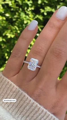 a woman's hand with a diamond ring on her finger and the other hand holding an engagement ring