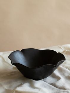 a black bowl sitting on top of a white sheet