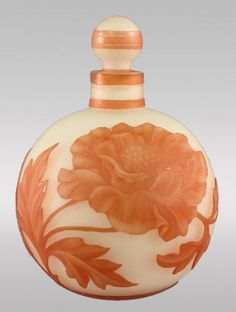 an orange and white vase with flowers painted on the front, sitting against a gray background