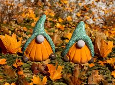 two green and orange gnomes sitting on top of leaves in the grass with their eyes closed