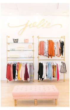 a clothing store with clothes on racks, and a bench in front of the rack