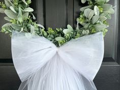 a wreath with white tulle and greenery on the front door