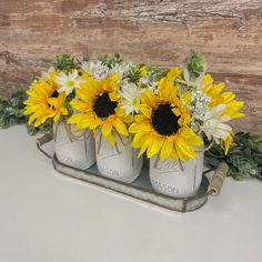 four mason jars with sunflowers and baby's breath in them on a table