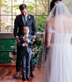 a man in a suit and tie standing next to a little boy