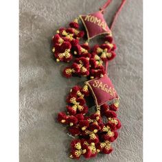 two red and gold flowers with name tags on them sitting on a gray cloth covered surface