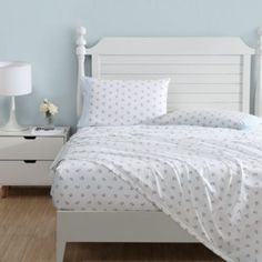 a white bed sitting next to a night stand on top of a hard wood floor