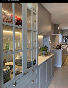 a kitchen filled with lots of white cabinets and counter top covered in plates and bowls