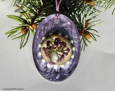 an ornament hanging from a tree decorated with grapes and pine cones