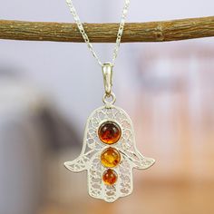 The Hamsa is an ancient amulet intended to protect against the evil eye. The Del Toro family handcrafts this 925 sterling silver pendant necklace embellished with amber stones that symbolize courage and self-confidence. This necklace will accompany you in your daily life as a protection and as a symbol of your courage and hardworking spirit. Traditional Sterling Silver Nickel Free Necklace, Traditional Nickel-free Sterling Silver Necklace, Hallmarked Amber Round Necklace, Spiritual Sterling Silver Charm Necklace With Gemstone, Sterling Silver Pendant Charm Necklace For Healing, Baltic Amber Gemstone Necklaces, Spiritual Round Amber Jewelry, Baltic Amber Pendant Necklace, Amber Healing Amulet Jewelry