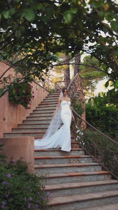 a woman in a wedding dress walking down some stairs