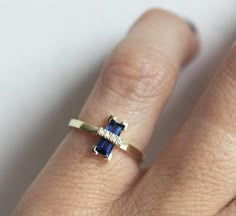 a woman's hand with a ring on it that has a blue and white stone in the middle