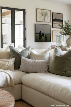 a living room filled with lots of pillows on top of a white couch next to a window