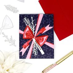 a card with a red bow and ribbon on it next to some paper snowflakes