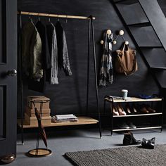 a room with black walls and wooden stairs, shoes hanging on the wall, an open door to another room