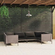 an outdoor living area with couches and potted plants on the side of it