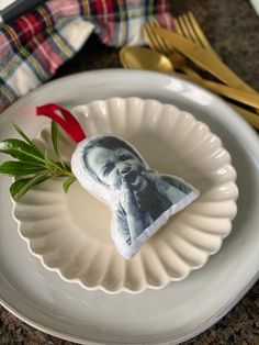 an ornament on a plate with a fork and knife next to it in the shape of a photo