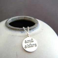 sterling silver soul sisters necklace, 1/2" - Sterling silver soul sisters circle charm, measuring 1/2" (13 mm) across, a nice 18 gauge thick (1 mm). - "soul sisters" is blackened (oxidized) to stand out. - Perfectly aligned letters, as the pendant is engraved, not hand stamped.  - Necklace is 1.5 mm sterling silver cable chain, with high quality lobster clasp and locking jump rings, all solid sterling silver.  - Shiny both sides, back is smooth, with a tiny 925 mark.  - With sustainability in mind, charm is made from 100% post-consumer recycled sterling silver. - Packaged in a modern circular tin, ready for gift giving, and comes with a silver polish pad and care instructions. Customize chain length or "charm only" option: - Charm only option, no chain. Charm does include a top ring. - Ch Sister Circle, Sisters Necklace, Cursive Words, Best Friend Forever, Word Necklace, Sister Jewelry, Sister Necklace, Silver Polish, Top Rings