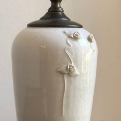 a white vase sitting on top of a wooden table next to a black and gold lamp