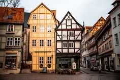 a cobblestone street with tables and chairs in front of old buildings on either side