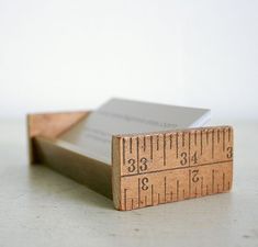 a wooden ruler with two pieces of paper on top of it and one piece of wood sticking out of the side