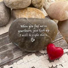 a rock with a heart on it sitting in front of some rocks and stones that say, when you feel me in your heart, just look up a will be right there