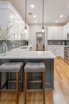 a kitchen with two stools next to an island in the middle of the room