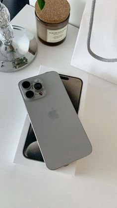 an iphone 11 pro sitting on top of a white table next to a bottle of wine