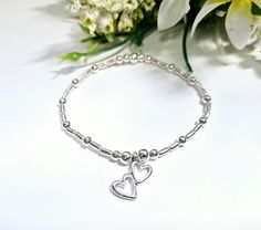 This is a beautiful handmade stretch beaded stacking bracelet that is lovingly made to a high standard using 4 mm silver-plated beads and tubes that are highlighted with 5mm round silver plated beads. Its then finished perfectly with a beautiful silver openwork double heart charm.  This bracelet can also be bought as part of a bracelet set. See pictures.  Perfect gift for someone special. Or maybe a a treat for yourself 🙂 Bracelets are made to 18cm approximately. Adjustments can be made to suit Adjustable Silver Stretch Bracelet With Heart Beads, Silver Stretch Bracelet With Heart Beads For Valentine's Day, Silver Stretch Bracelet With Heart Beads As Gift, Dainty Stretch Bracelet With Heart Beads For Gift, Silver Stretch Bracelet For Valentine's Day, Mother's Day Friendship Heart Beads Stretch Bracelet, Mother's Day Friendship Bracelet With Heart Beads, Adjustable Heart Beads Bracelet For Anniversary, Adjustable Beaded Bracelets With Heart Charm For Wedding