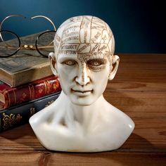 a white mannequin head sitting on top of a table next to some books