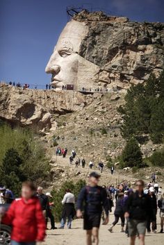 many people are walking around in front of a large statue