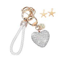 a heart shaped keychai with two charms attached to it, one is white and the other has gold