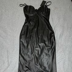 a black leather dress laying on top of a white sheet covered floor next to a pair of scissors