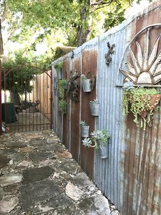 an old fence with potted plants on it and a sun decoration above the gate