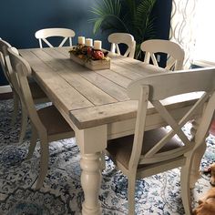 a dog laying on the floor in front of a table with chairs and a tray of food