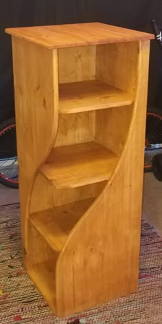 a wooden book shelf sitting on top of a rug next to a bicycle tire rack