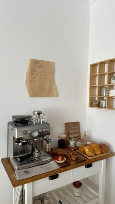 a coffee maker sitting on top of a wooden table next to a shelf filled with pastries