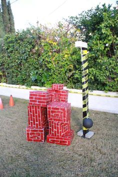 some red bricks and a black ball in the grass near trees with orange cones around them