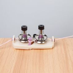 two small metal objects sitting on top of a wooden table next to a string attached to it