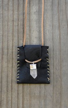 a small black bag hanging on the side of a wooden wall with a white tag attached to it