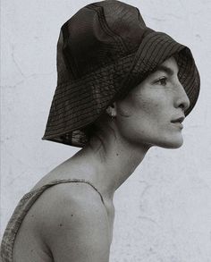 a woman with a hat on her head is looking off to the side in black and white