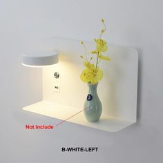 a vase with yellow flowers in it sitting on a shelf next to a wall light