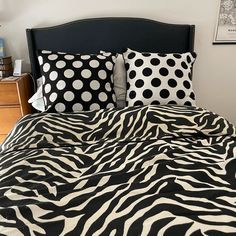 a black and white bed with zebra print sheets