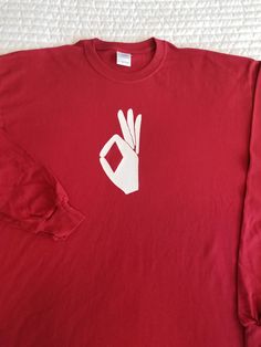 a red long sleeved shirt with a white peace sign on the front and two fingers in the middle