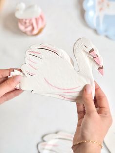 a person holding a paper cut out of a swan on top of a white table