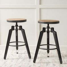 two stools in front of a white wall with wood and metal trim on the legs