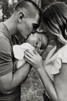 a man and woman kissing while holding a baby