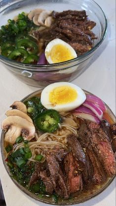 two bowls filled with meat, vegetables and an egg on top of each bowl next to another bowl