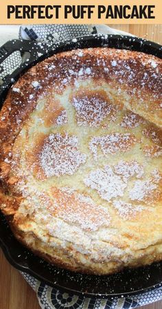 a pancake with powdered sugar on top in a cast iron skillet sitting on a table